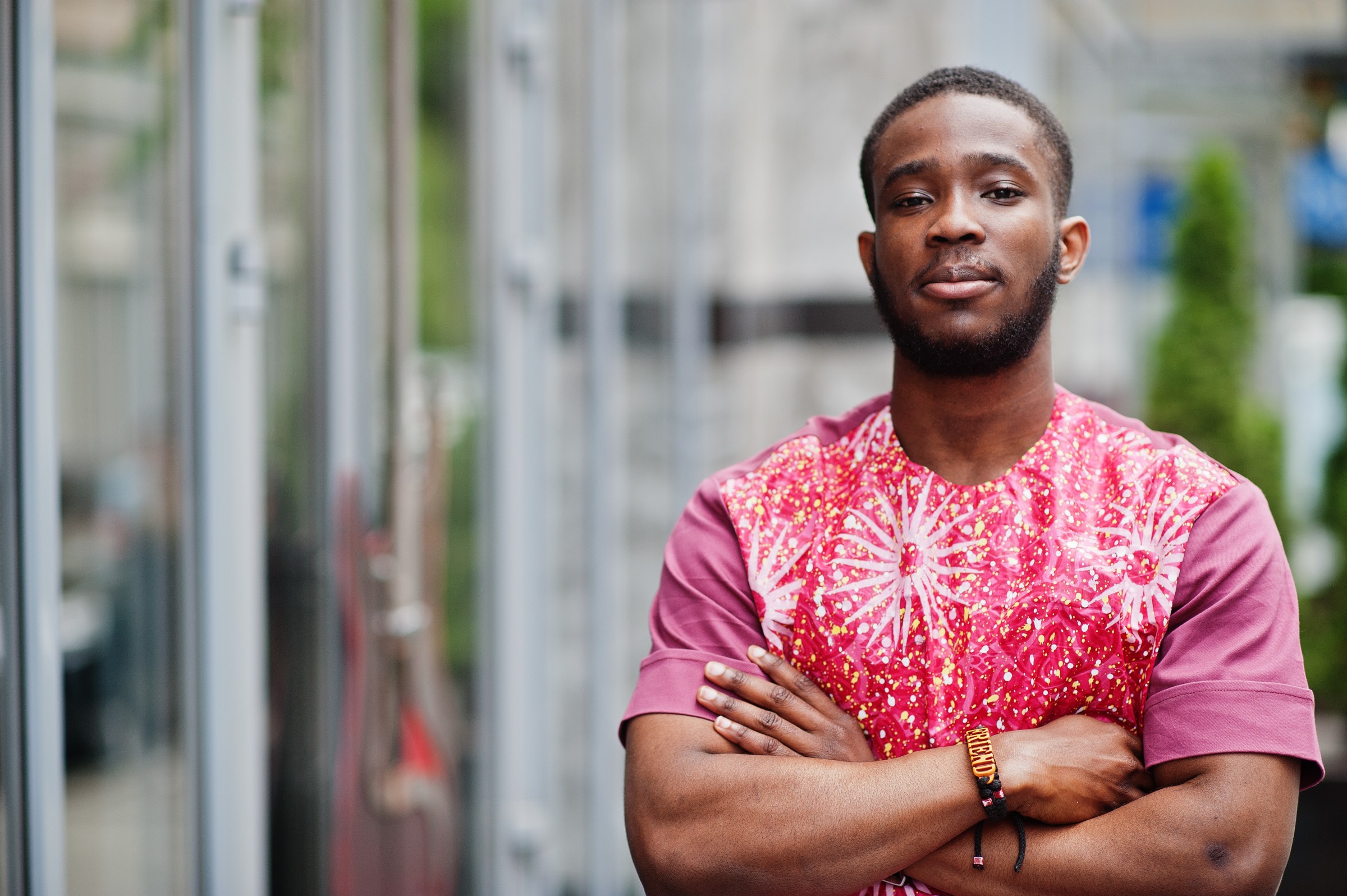 Young man in a brightly patterned shirt standing with arms crossed